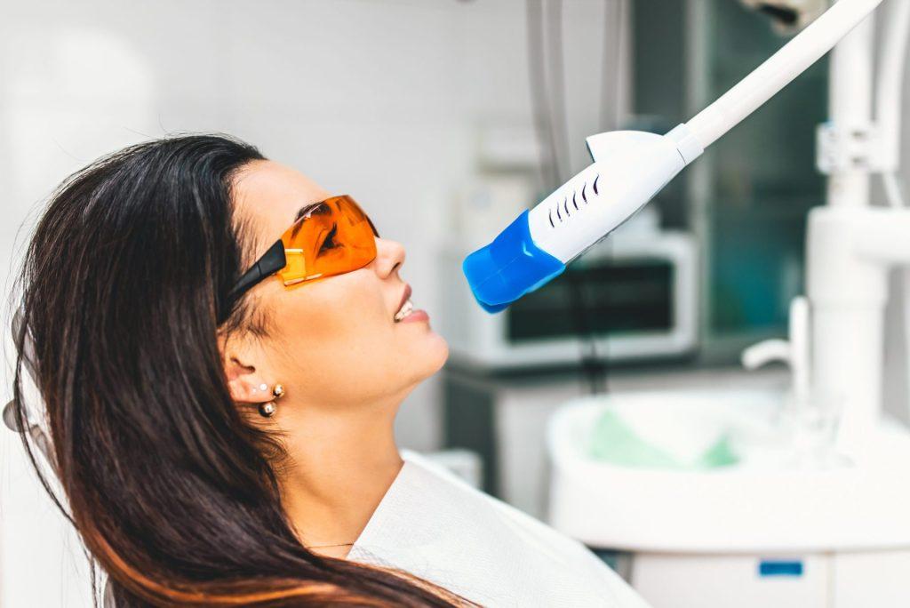 Smiling patient in protective glasses before a whitening light treatment