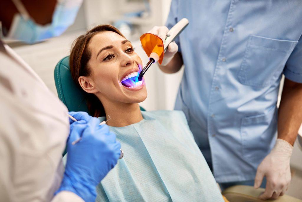 Patient smiling as a curing light is used on her teeth