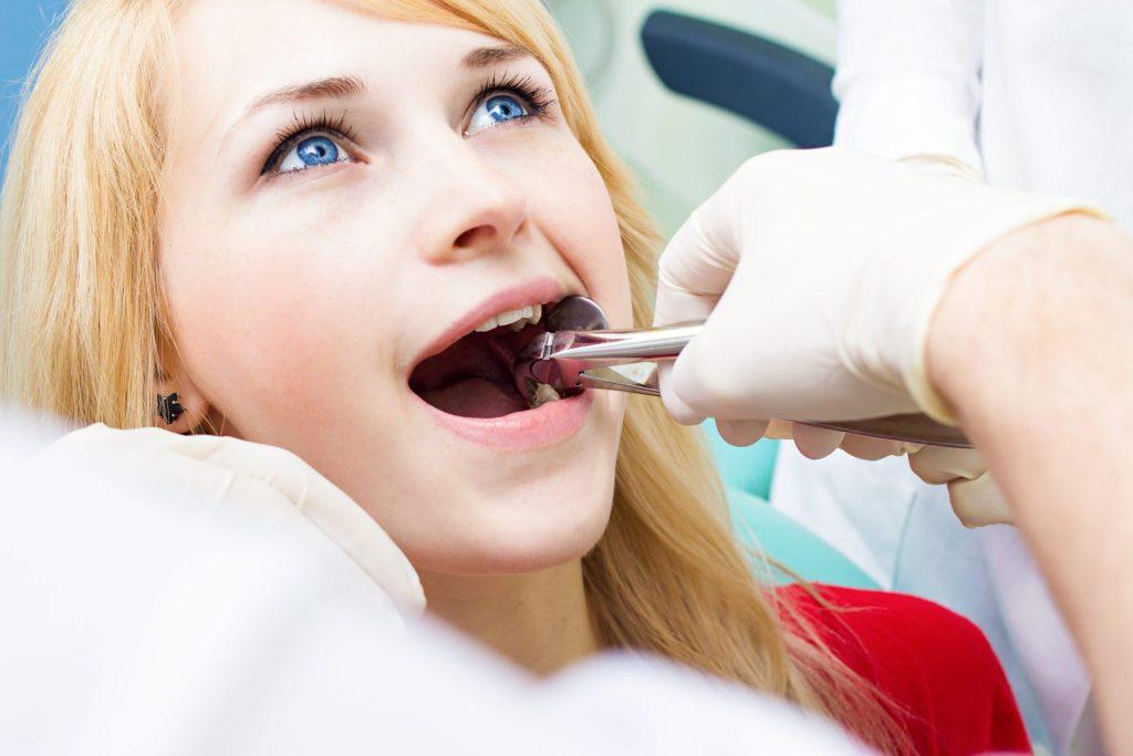 Patient opening wide while a dentist works with dental instruments