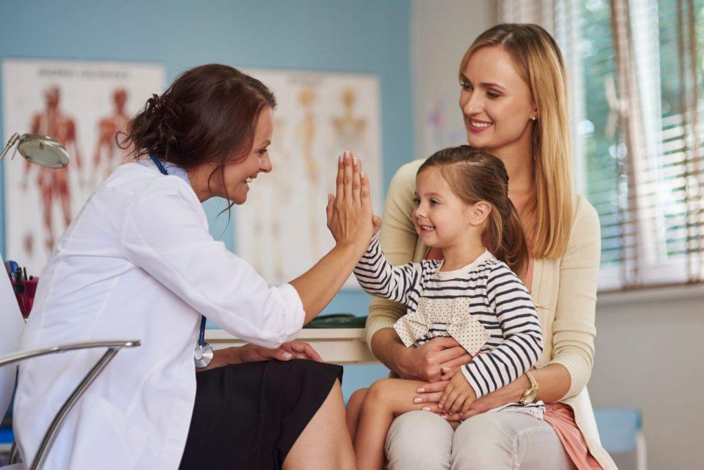Young girl giving a high five to a dentist while her mother watches