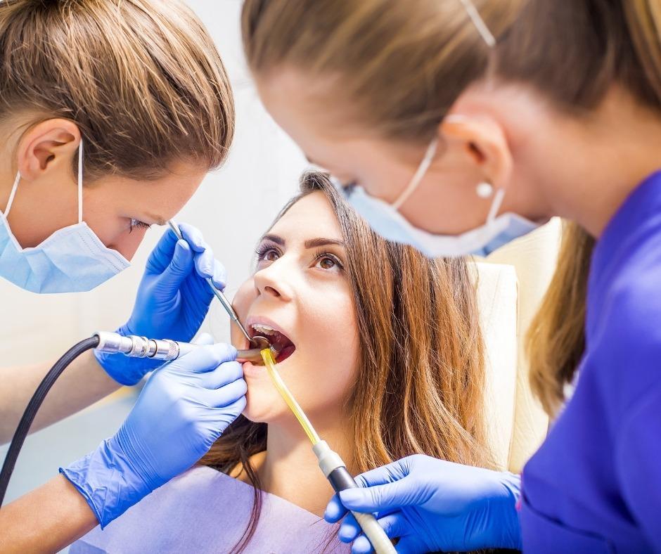 Patient having her teeth worked on by a dentist and assistant