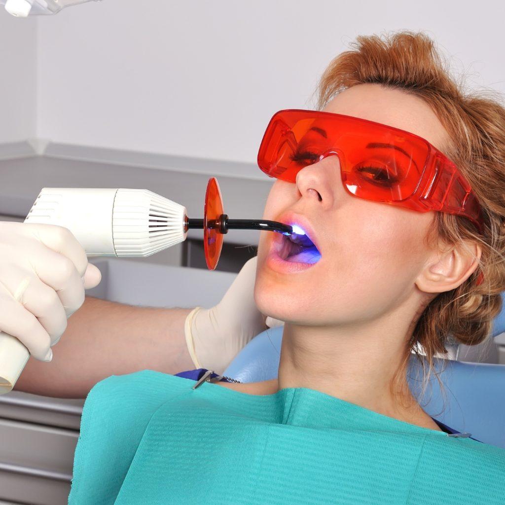 Patient in protective glasses while a curing light sets a filling