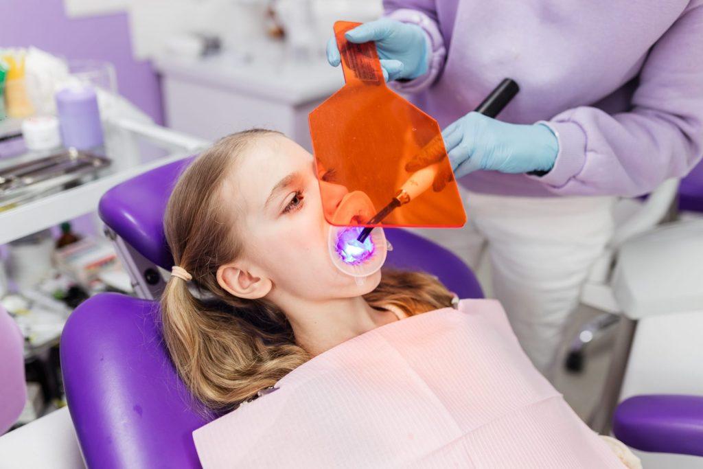 Young patient wearing glasses as a curing light sets a filling