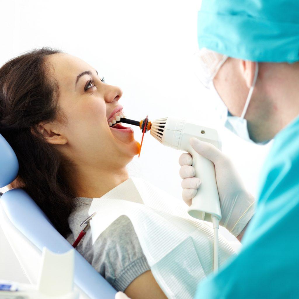 Patient in the dental chair as a dentist uses a curing light