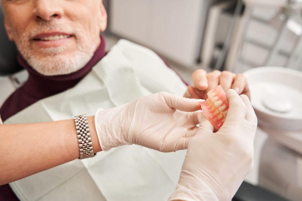 Dentist handing a patient his denture