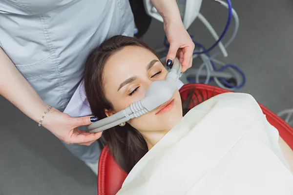 Smiling patient with eyes closed wearing a nitrous oxide nose mask