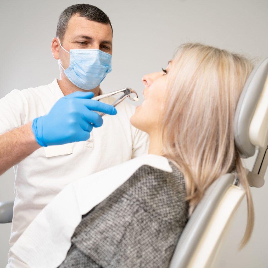 Dentist in a mask examining a patient's teeth
