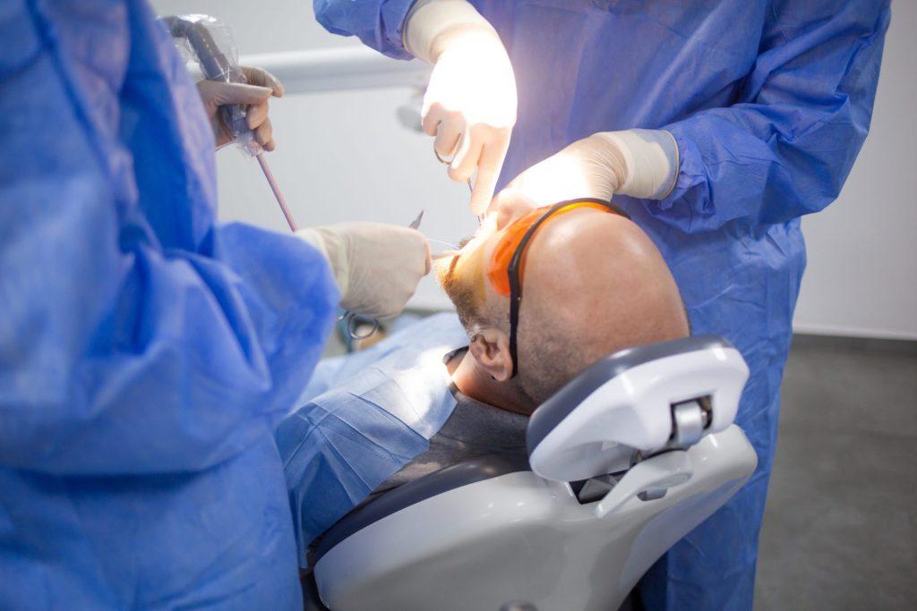 Oral surgeons performing a procedure on a sedated patient