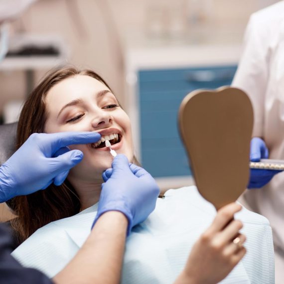Patient checking her smile in a hand mirror at the dentist