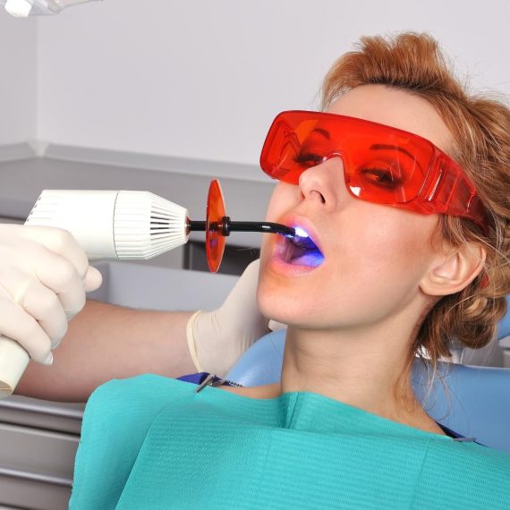 Patient in protective glasses while a curing light sets a filling